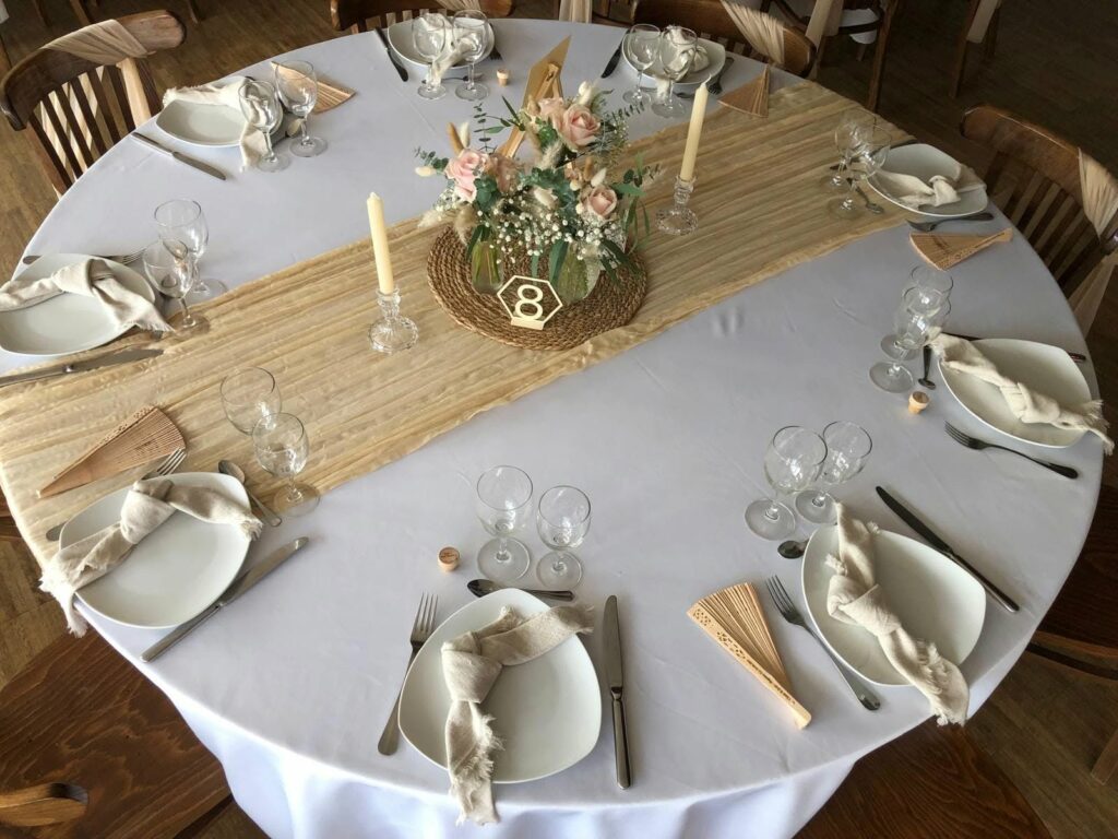 Table ronde dressée avec chemin de table et fleurs