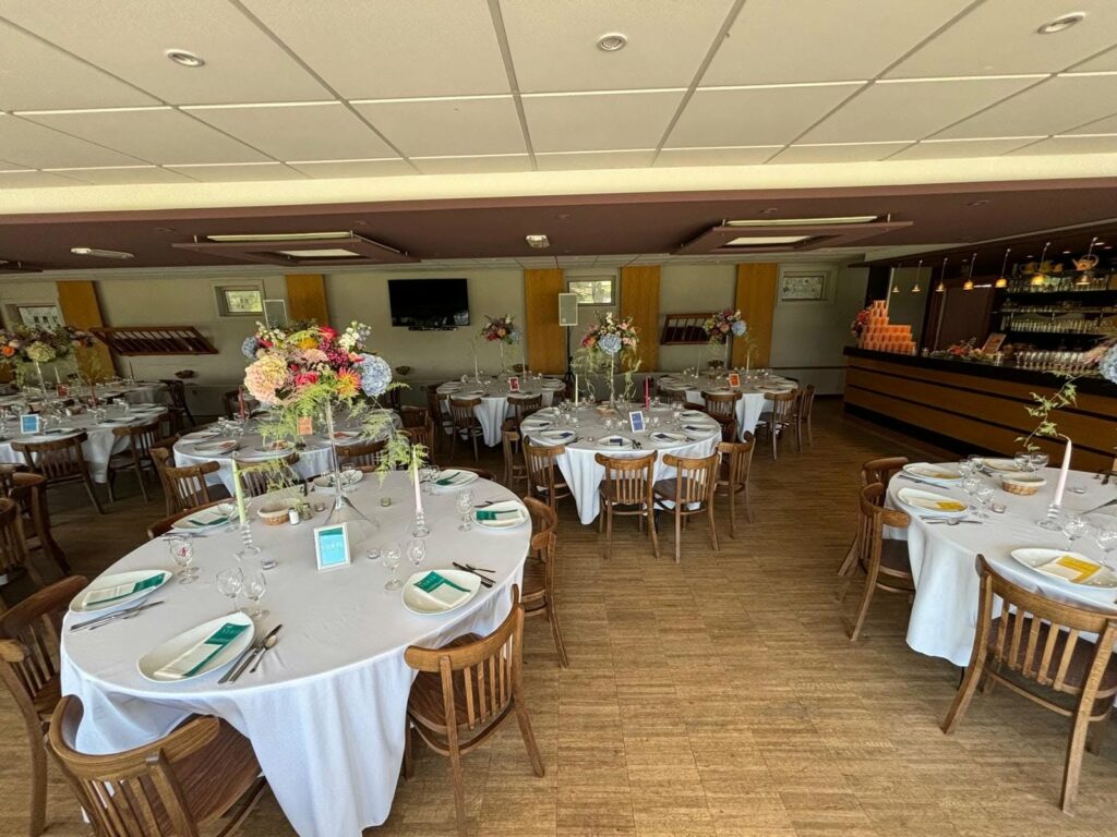 La salle dressée avec des tables rondes pour un repas